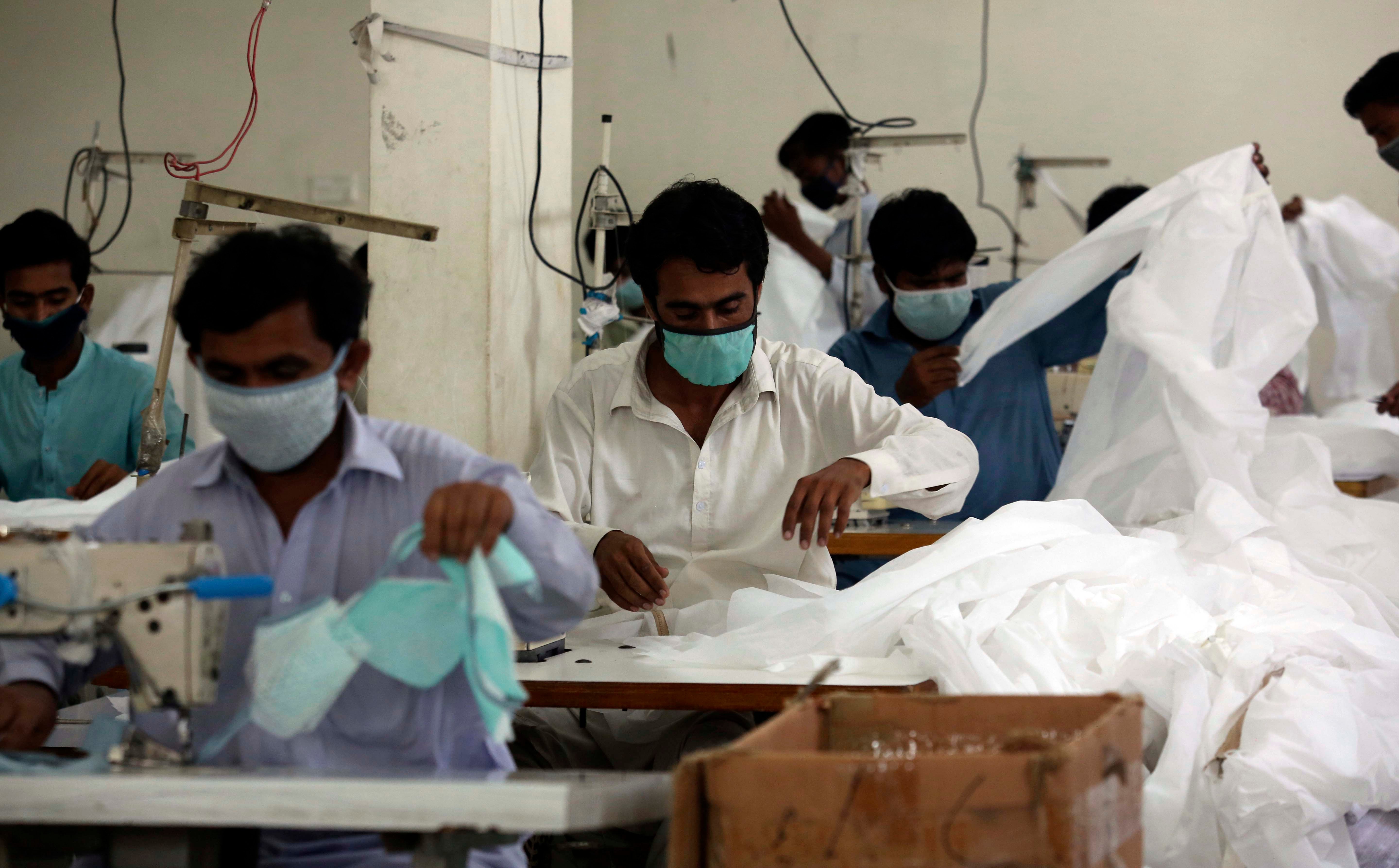 Pakistani workers make face masks, which are in great demand worldwide due to the outbreak of the coronavirus, in Karachi, Pakistan, March 31, 2020. © 2020 AP Photo/Fareed Khan  