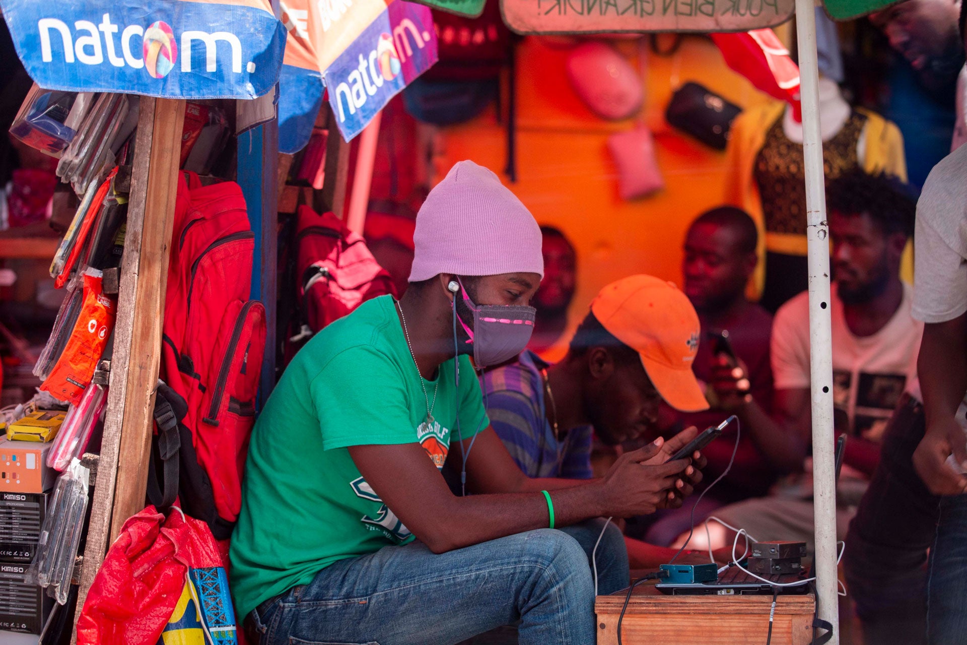 A street seller checks his phone while wearing a mask to protect himself from the spread of the new coronavirus, in Port-au-Prince, Haiti, Monday, March 23, 2020.