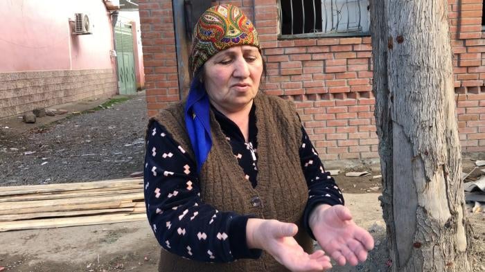 Woman being interviewed stands in front of building.