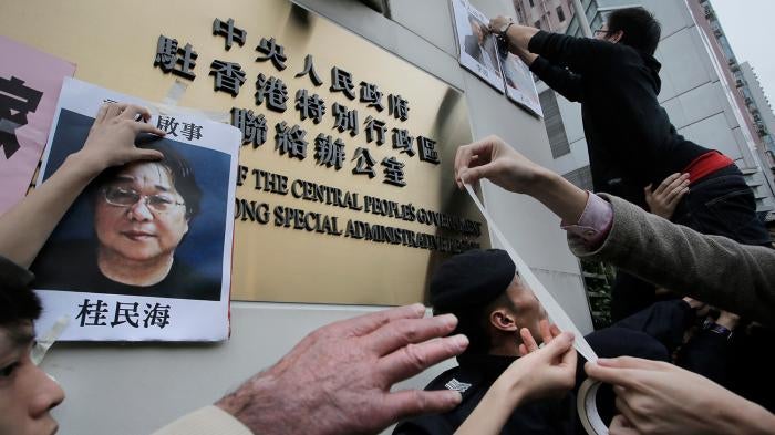 Protesters stick photos of Gui Minhai, left, and other missing booksellers outside the Liaison Office of the Central People's Government in Hong Kong on January 3, 2016.