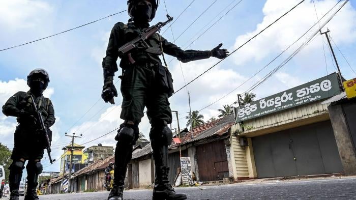 Two uniformed police officers gesture in a road