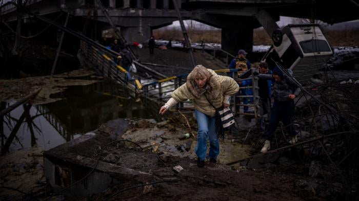 People flee across a destroyed bridge on the outskirts of Kyiv, Ukraine, March 2, 2022.