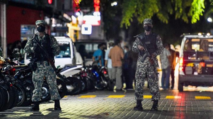 Armed police officers stand in a road