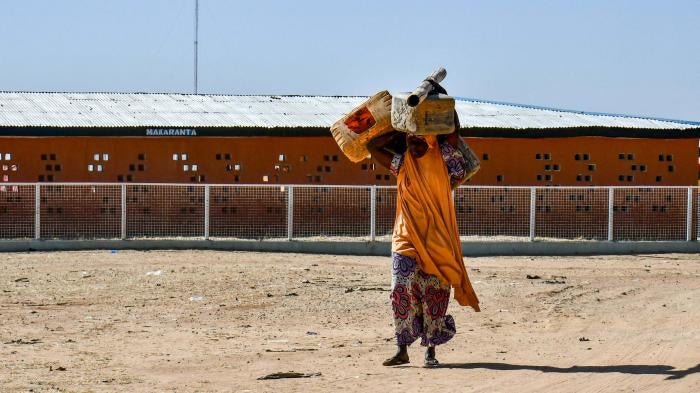 A woman carries belongings over her head
