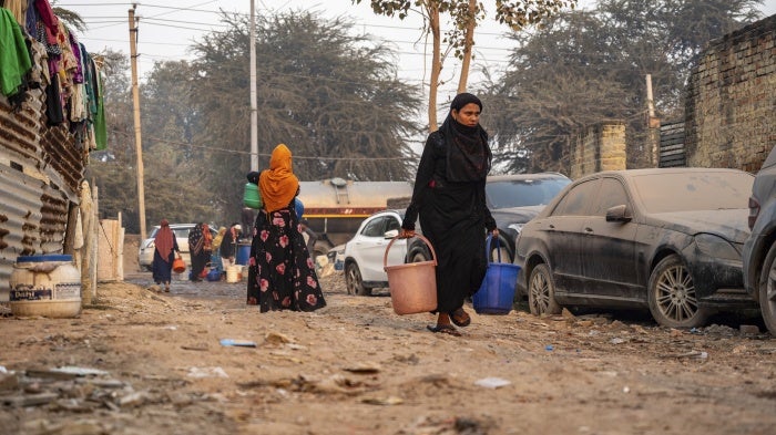 A Rohingya woman carries drinking water in Madanpur Khadar refugee camp, India, January 14, 2024.