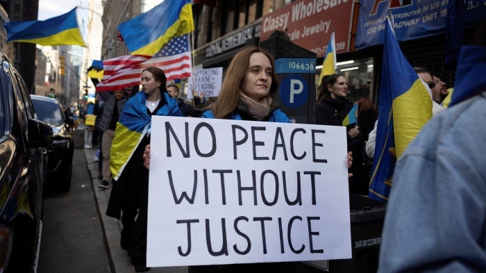 A demonstrator holds a sign that reads "No Peace Without Justice" at a protest