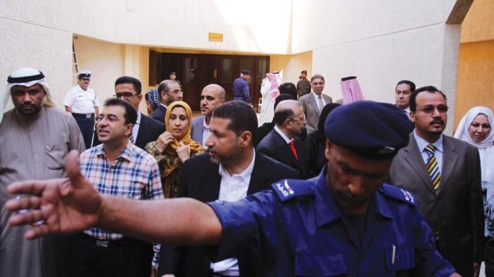 A police officer holds back journalists as doctors and nurses emerge during a break in their civilian criminal court trial on November 28, 2011 in Manama, Bahrain.
