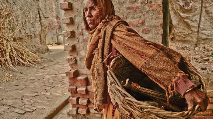 Gangashree walks through the village to manually clean human excrement from dry toilets in Kasela, Uttar Pradesh, which she will collect in her basket and carry to the outskirts of the village for disposal. 