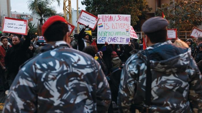 In this Sunday, Feb. 22, 2009 picture, Lebanese police stand guard as protesters carry banners during a sit-in for gays and lesbians in Beirut. 