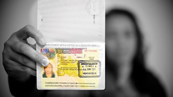 A domestic worker holds up her UK Overseas Domestic Worker visa. Following changes to the immigration rules in April 2012, workers entering the UK on this visa are not permitted to change employer, making them more vulnerable to abuse.
