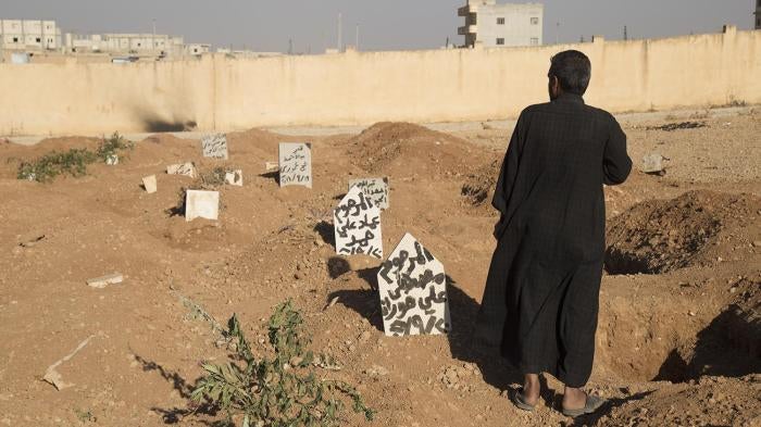 A family member stands next to the graves of three children who were killed when an explosive device planted by ISIS in a school in Manbij detonated on September 27.  