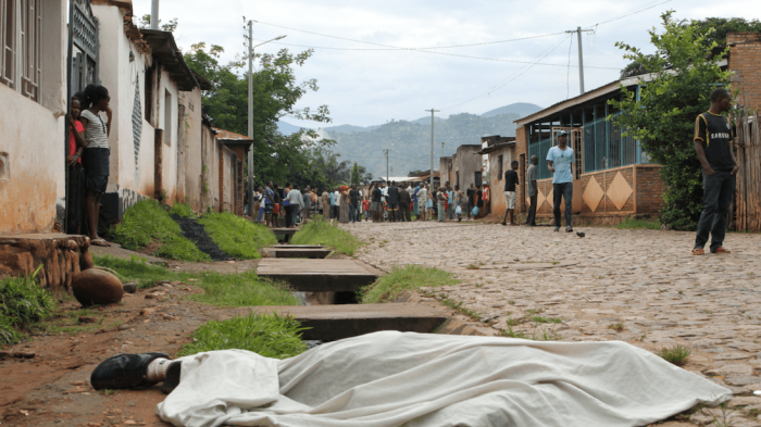 Residents outside their houses in Nyakabiga, in the Burundian capital Bujumbura, look at the body of a man shot dead on December 11, 2015.