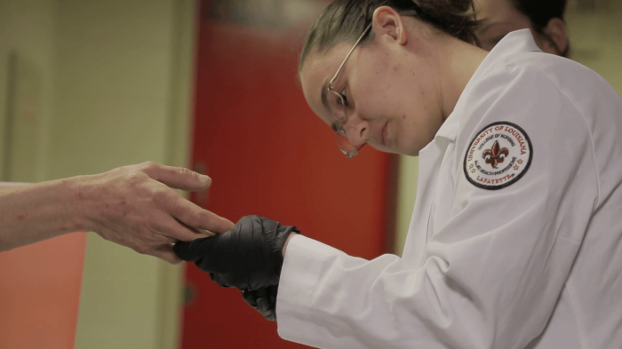 A nurse drawing blood from an inmate's finger for HIV testing.