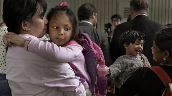 Two mothers hold their children in their arms as they wait outside the immigration department's building in Hong Kong, China.