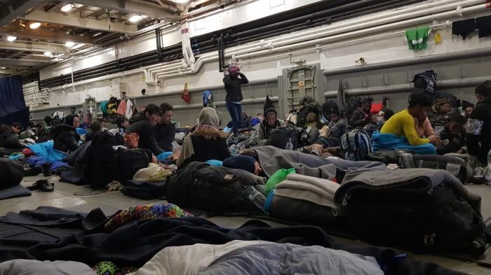 Women, men, and children inside the hull of a Greek Navy ship in Mytilene harbor, Lesbos, Greece. March 2020. © Private