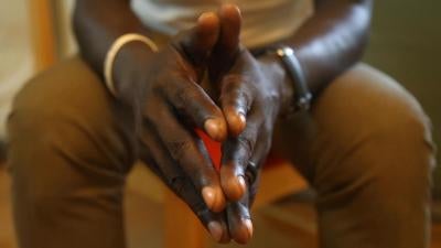 Clasped hands of interviewee are in focus in the foreground of the image