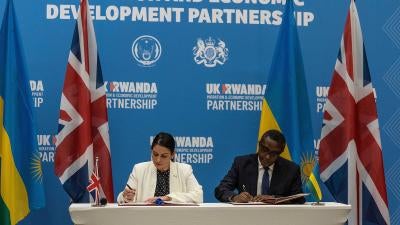 Then-British Home Secretary Priti Patel (L), and Rwandan Minister of Foreign Affairs and International Cooperation Vincent Biruta sign an agreement