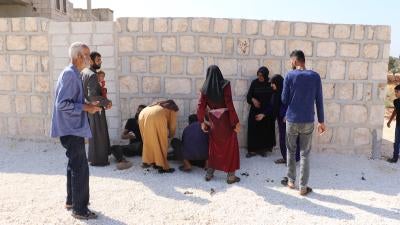 People gather around one of three people injured on October 7, 2023, after a nine-year-old picked up an unexploded submunition that detonated after he  dropped it the ground. The boy was severely injured, Termanin, Syria. 
