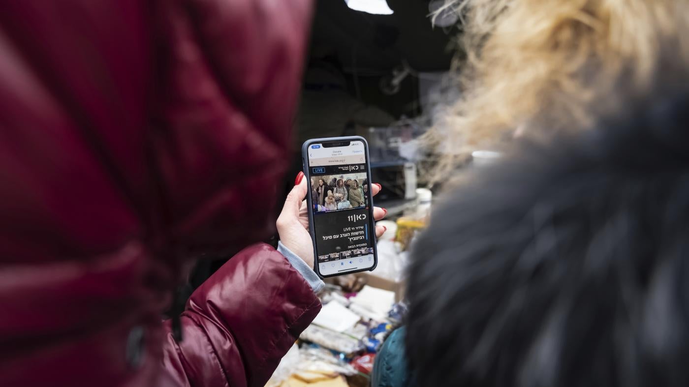 Two women from Kharkiv, Ukraine, watch news on a mobile phone, just after having crossed the border into Moldova, on March 10, 2022.