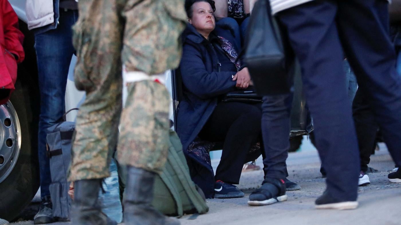A soldier stands in front of civilians 