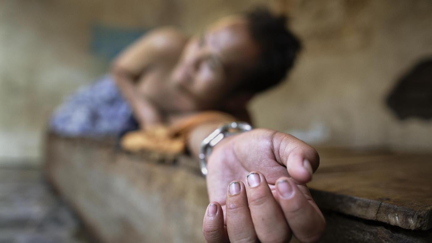 A man with a psychosocial disability lies chained at the wrist on a platform bed at the Bina Lestari healing center in Brebes, Central Java. All residents of the healing center are chained. © 2015 Andrea Star Reese for Human Rights Watch 