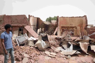 Man stands next to building destroyed during fighting in Khartoum, Sudan