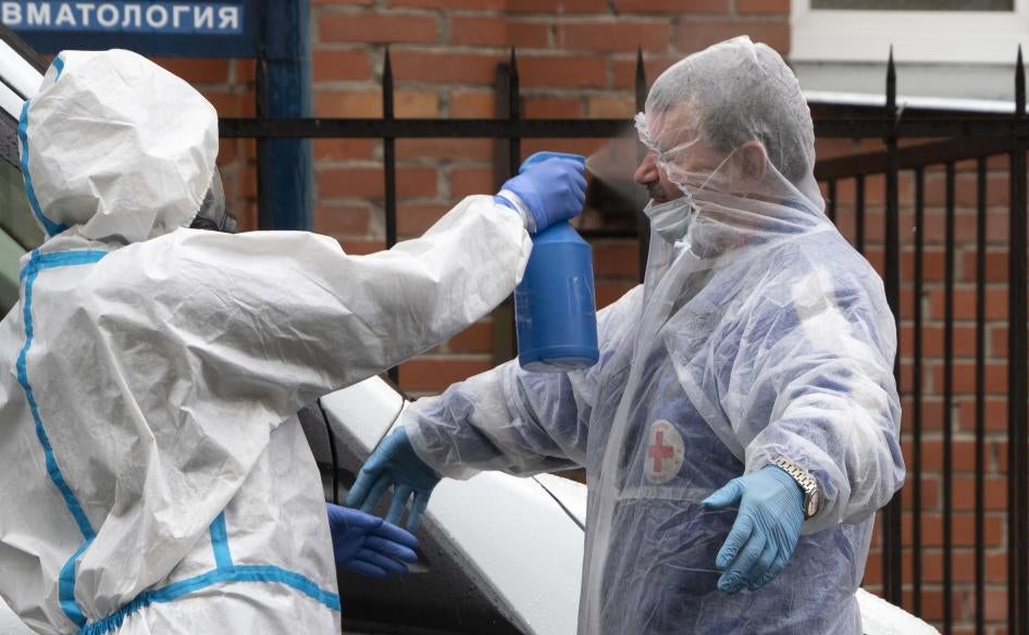 A medical worker wearing gear to protect against coronavirus disinfects an ambulance driver for a hospital treating COVID-19 patients in St.Petersburg, Russia, June 4, 2020.