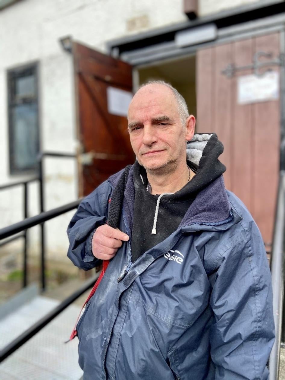 A man in a blue jacket stands outside of a building