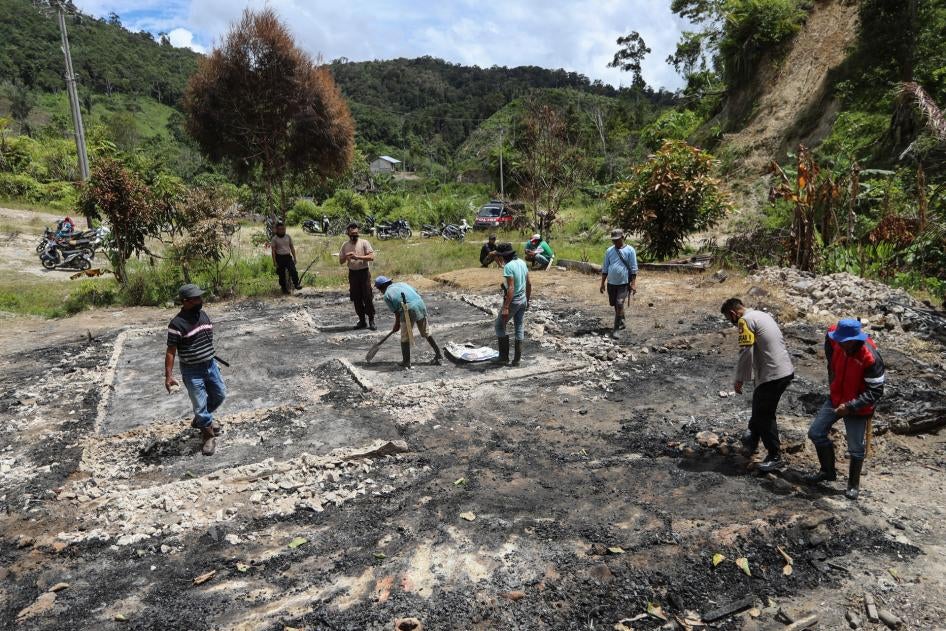 Villagers and police officers clean up debris at the site of suspected militant attack in Lembantongoa village in Sulawesi, Indonesia, November 30, 2020. 