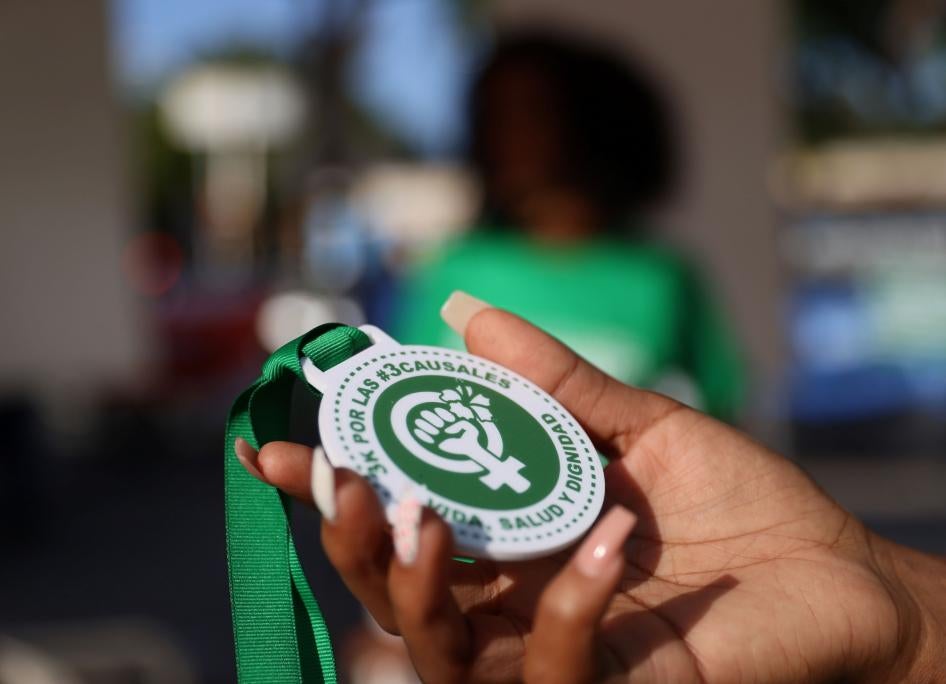An abortion rights activist holds a plastic medallion reading "For the #3Causales (#3LegalGrounds), Life, Health and Dignity" during a protest to urge parliament to approve a proposed reform to the penal code that could end the total ban on abortion, in Santo Domingo, Dominican Republic March 18, 2021. 