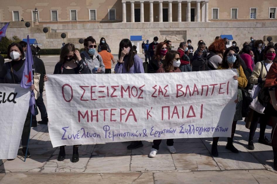 Protesters in Athens, Greece on March 27, 2021 stand outside the Greek Parliament displaying a banner that reads “your sexism is harming both mother and child” against a new law that introduces presumptive co-custody of children, even in cases of domestic violence.