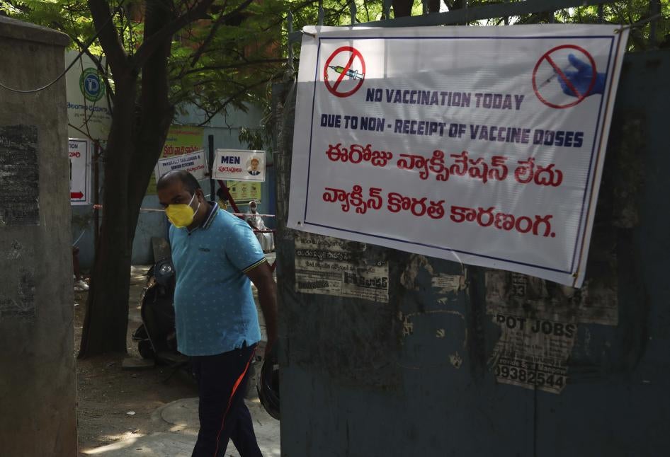 A man in a face mask stands next to a sign that says "No vaccination today" in English and Hindi