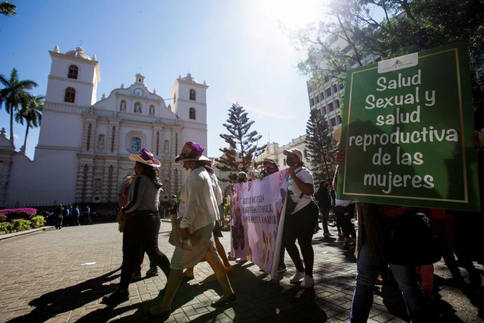 A demonstrator carries a sign reading "Women's sexual health and reproductive health" during a march to commemorate the right to vote and to celebrate the election of Honduras' first female president, in Tegucigalpa, Honduras, on January 25, 2022.