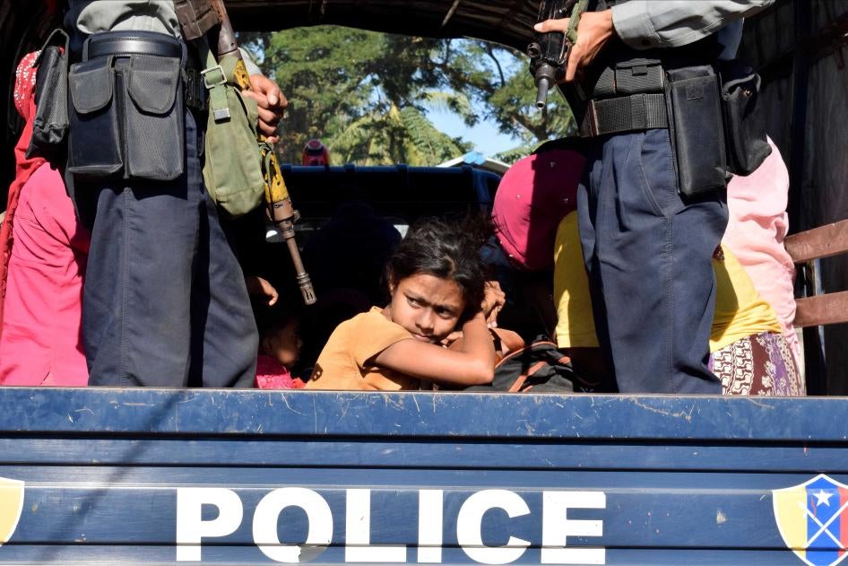 A person looks out from the back of a police truck