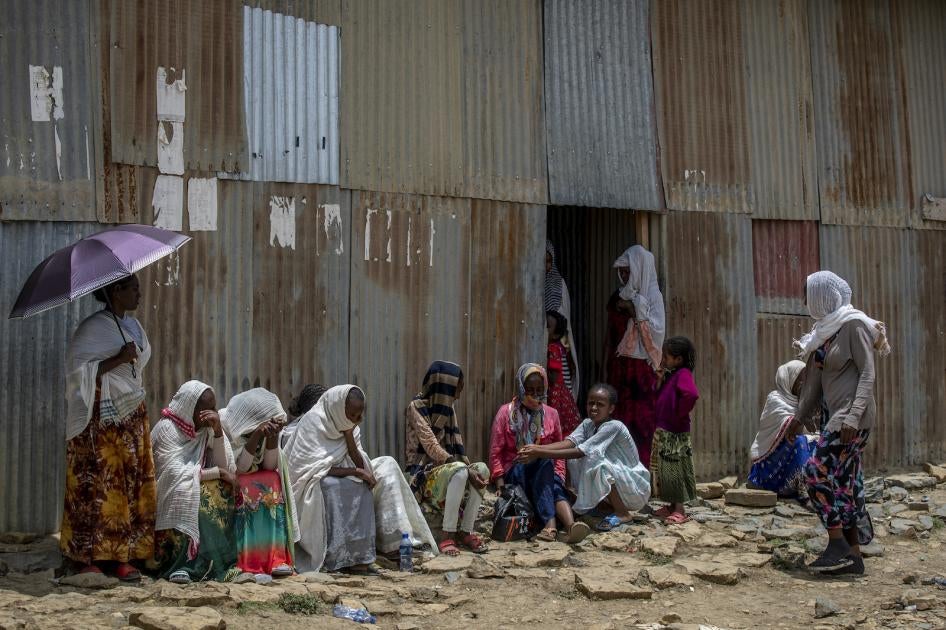 Displaced Tigrayans sit alongside metal shacks in Mekele, Ethiopia.