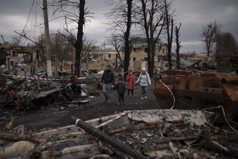 A family walks amid destroyed military vehicles in Bucha, near Kyiv, Ukraine, April 6, 2022. 