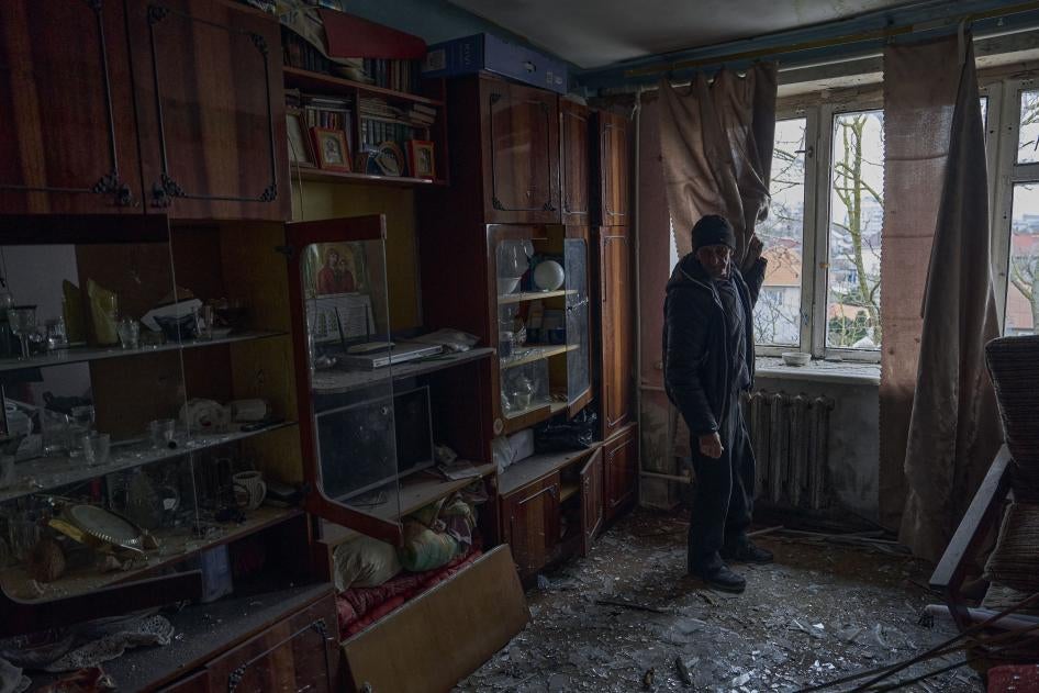 A man looks at shards of glass on his apartment floor 