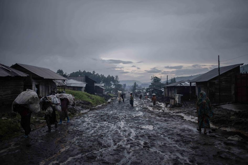 Après la pluie, des commerçants quittent le marché avec leurs sacs à Kitchanga