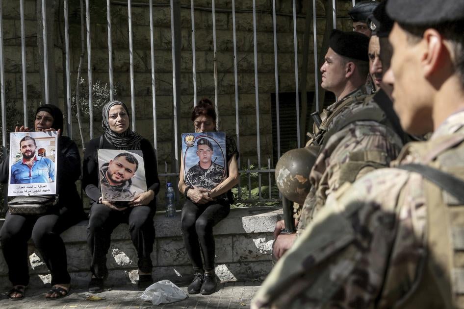 Families of the victims of the Beirut port blast hold pictures of their loved ones near Lebanese soldiers during a protest outside of the Beirut court, September 27, 2022. 