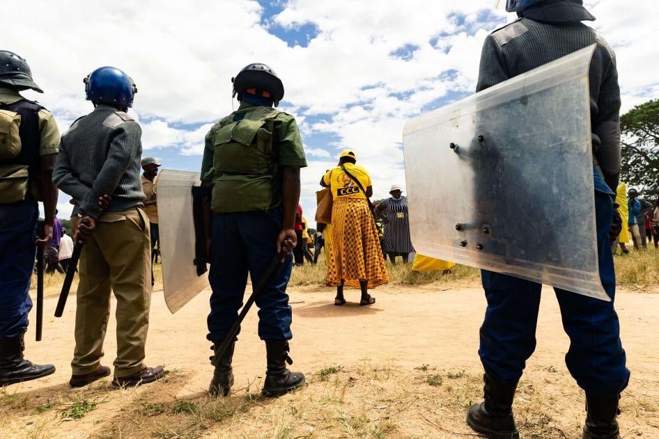 A line of police with riot shields stand in front of protestors