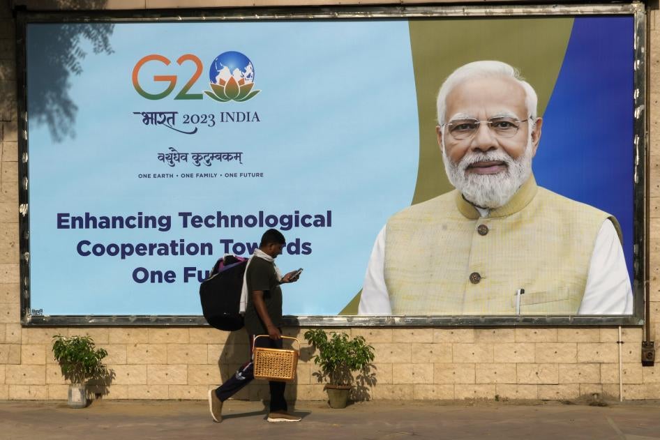 A migrant laborer walks past a billboard ahead of the summit of the Group of 20 nations in New Delhi, September 4, 2023.