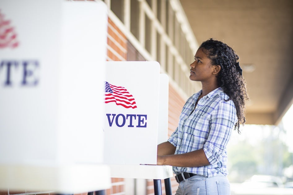 Une jeune femme noire vote le jour des élections.