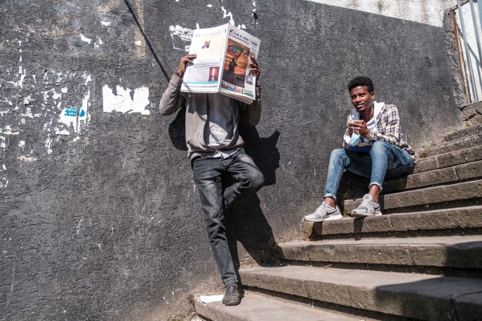 Un habitant d’Addis-Abeba, en Éthiopie, lisait un journal près d’un autre homme assis sur des marches, le 3 novembre 2021.