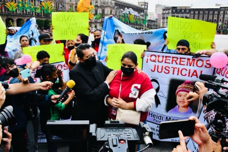 A woman in a medical mask addresses reporters at a protest