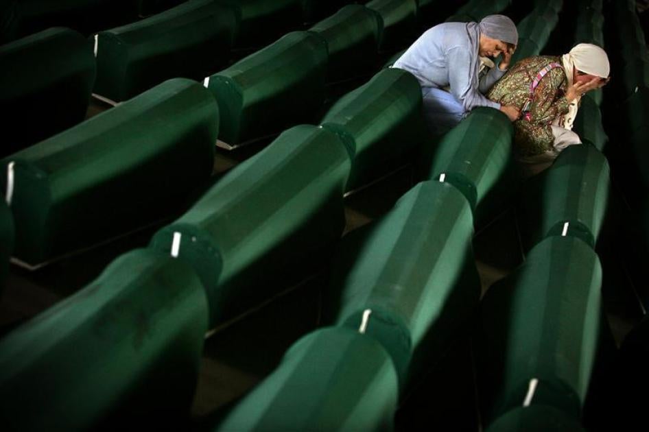 Two Bosnian Muslim women cry over a coffin July 10, 2005 with remains of their relative in a factory hall in Potocari where 610 victims of Srebrenica massacre wait for the funeral.