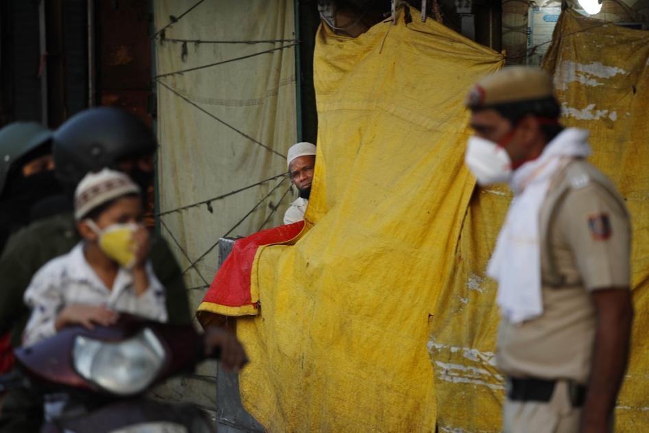 An Indian Muslim watches a policeman instructing a family riding on a scooter on social distancing on the first day of the holy month of Ramadan at the old quarters of New Delhi, India, Saturday, April 25, 2020. 
