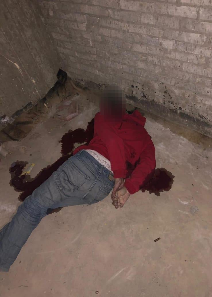 A blurred body lies on the floor in a pool of blood