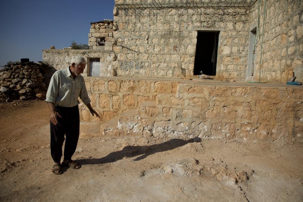 Muhammad Hammadi, the grandfather of a nine-year-old boy who suffered severe injuries from the accidental detonation of an unexploded explosive submunition on October 7, is pictured here pointing to the location where the incident occurred in Termanin, Syria, on October 14, 2023.
