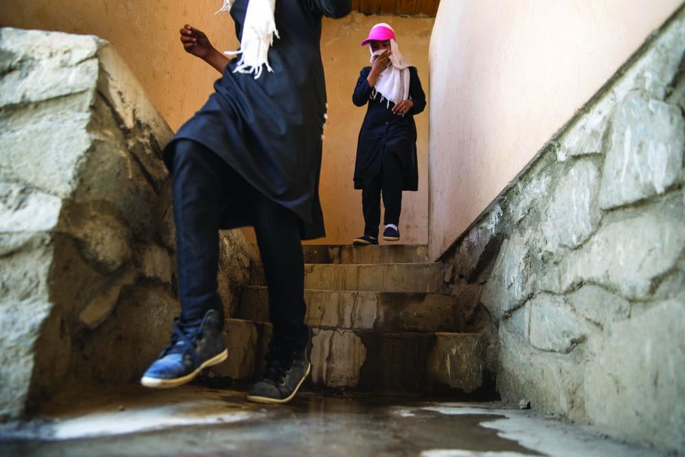 Girls cover their faces to protect themselves from the stench of a filthy and malfunctioning restroom in their school.