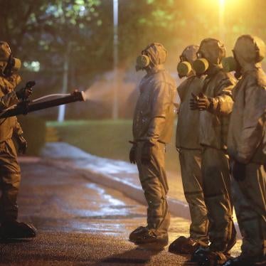 Servicemen of Belarus Ministry of Defence wearing protective gear spray disinfectant on each other after disinfecting a hospital in Minsk